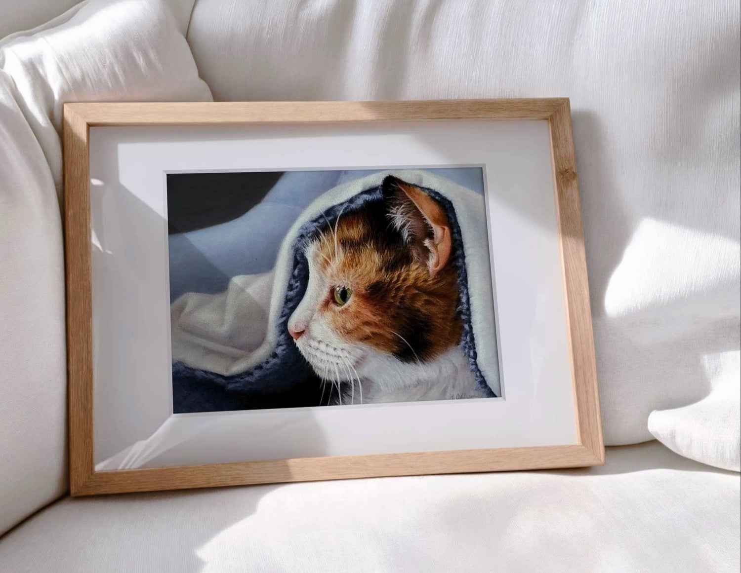 Framed hyper-realistic pastel drawing of a calico cat on a couch